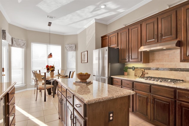 kitchen featuring pendant lighting, light tile patterned floors, crown molding, stainless steel appliances, and a kitchen island