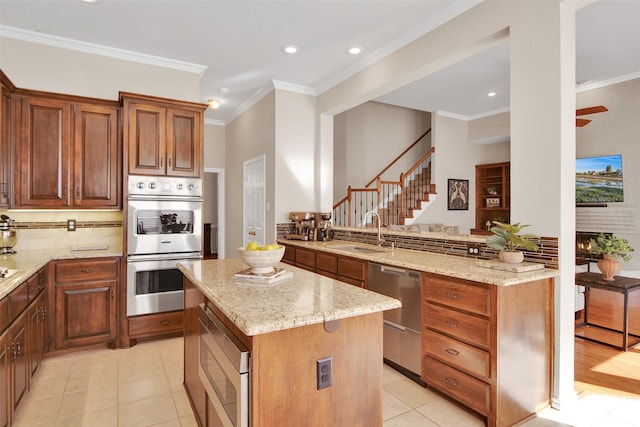 kitchen with appliances with stainless steel finishes, a sink, light stone counters, and tasteful backsplash