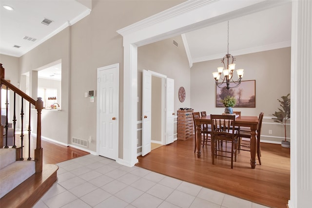 dining space featuring light tile patterned floors, visible vents, ornamental molding, an inviting chandelier, and stairs