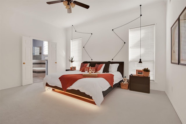 carpeted bedroom featuring multiple windows, ensuite bathroom, and ceiling fan