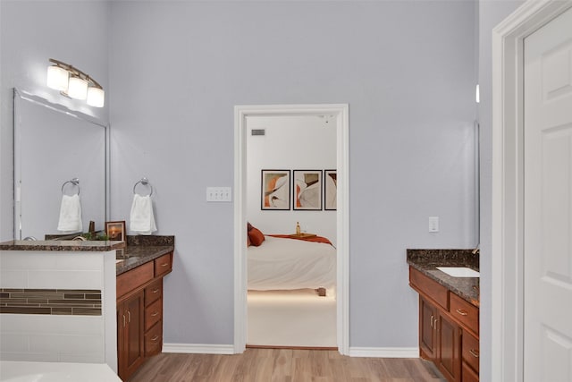 bathroom with vanity, baseboards, connected bathroom, and wood finished floors