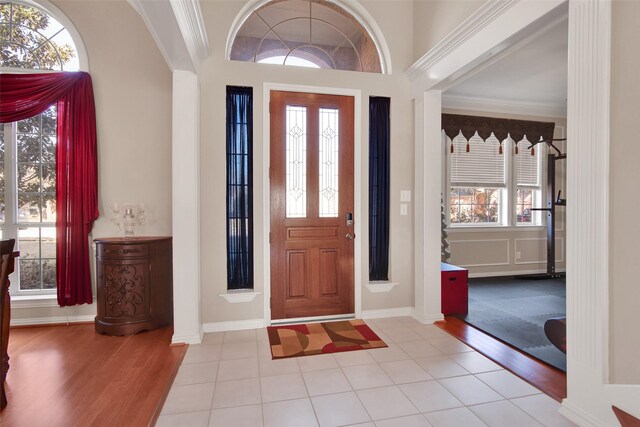 tiled foyer featuring crown molding and ceiling fan