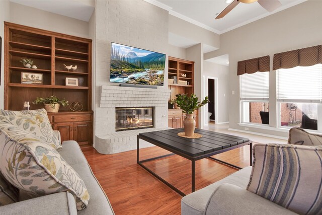 living room with a notable chandelier, a brick fireplace, a towering ceiling, and light hardwood / wood-style floors