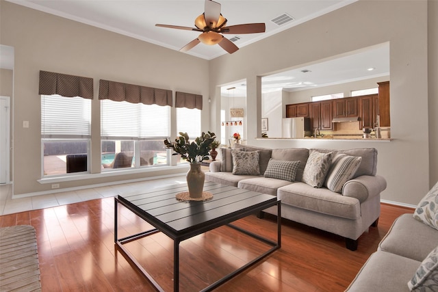 living area featuring light wood finished floors, visible vents, and crown molding