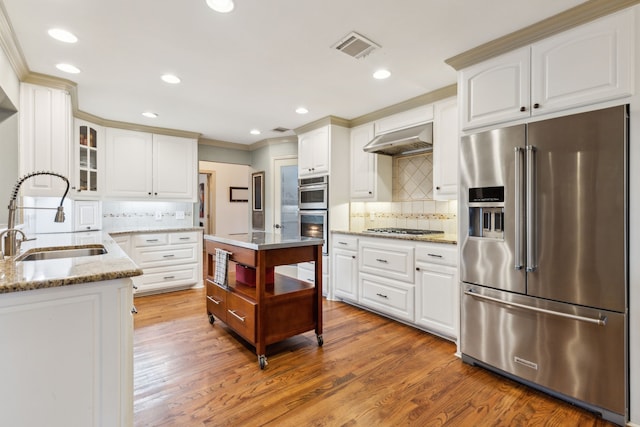 kitchen with stainless steel appliances, sink, white cabinetry, tasteful backsplash, and exhaust hood