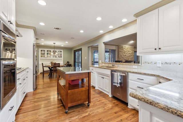 kitchen featuring white cabinets, stainless steel dishwasher, hanging light fixtures, and sink