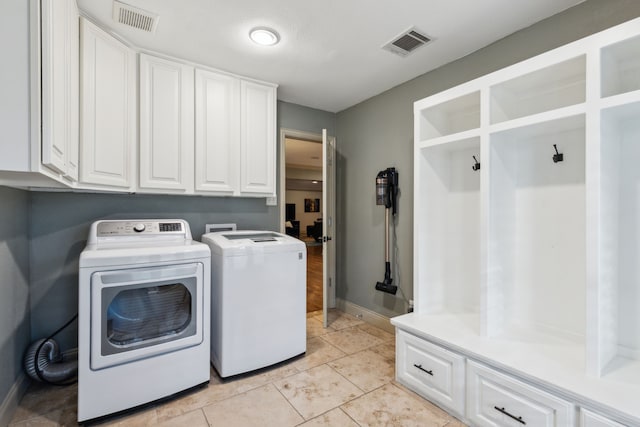 clothes washing area featuring independent washer and dryer, cabinets, and light tile patterned floors