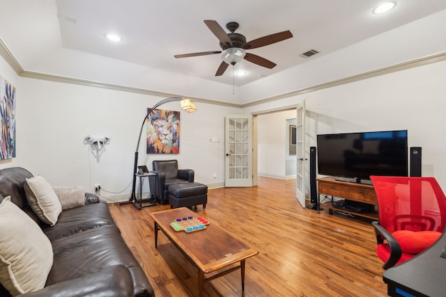 living room with wood-type flooring, ceiling fan, french doors, and a tray ceiling