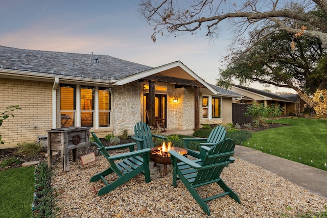 back house at dusk with a fire pit and a yard