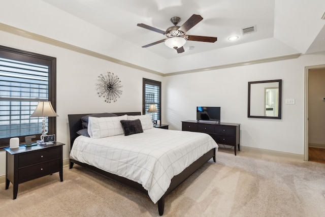 carpeted bedroom featuring multiple windows, ceiling fan, and a tray ceiling