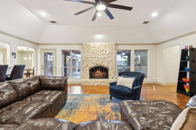 living room with lofted ceiling, hardwood / wood-style flooring, and a stone fireplace