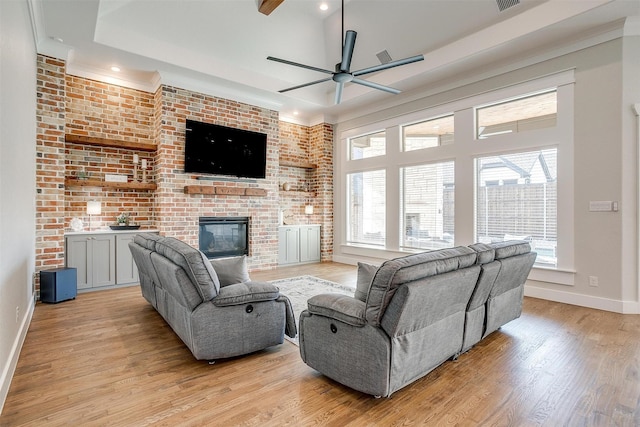 living area featuring light wood-style floors, a fireplace, baseboards, and a wealth of natural light