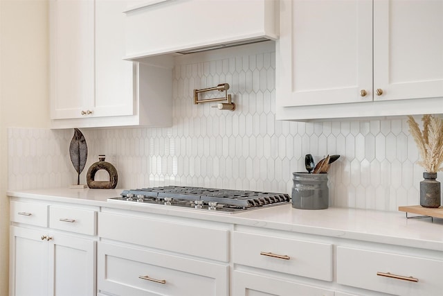 kitchen with stainless steel gas cooktop, light countertops, tasteful backsplash, and white cabinetry