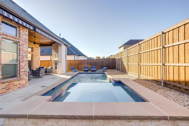 view of patio / terrace with ceiling fan, a fenced in pool, and an outdoor stone fireplace