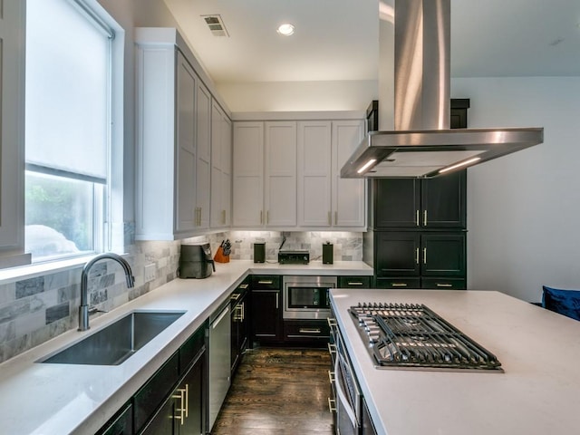 kitchen featuring island range hood, dark hardwood / wood-style floors, stainless steel appliances, tasteful backsplash, and sink