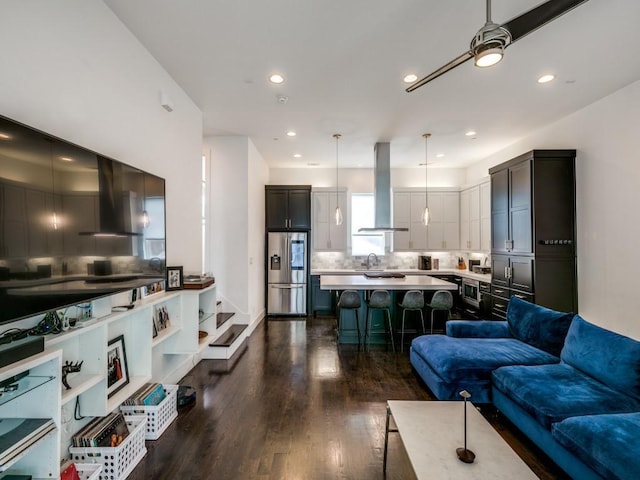 living room featuring sink, dark wood-type flooring, and ceiling fan