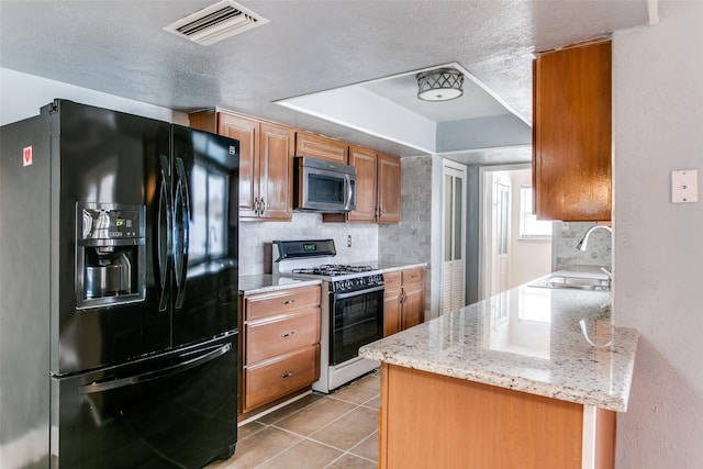 kitchen featuring sink, light tile patterned flooring, black fridge with ice dispenser, light stone counters, and gas range