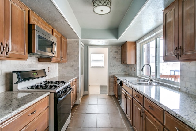 kitchen featuring light tile patterned floors, range with gas cooktop, light stone counters, and sink