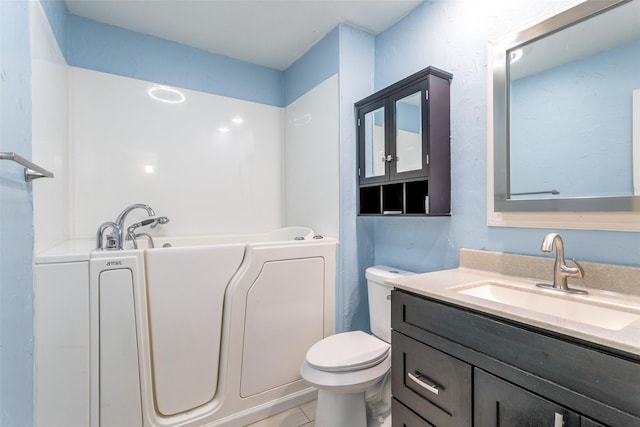 bathroom featuring a washtub, toilet, vanity, and tile patterned flooring