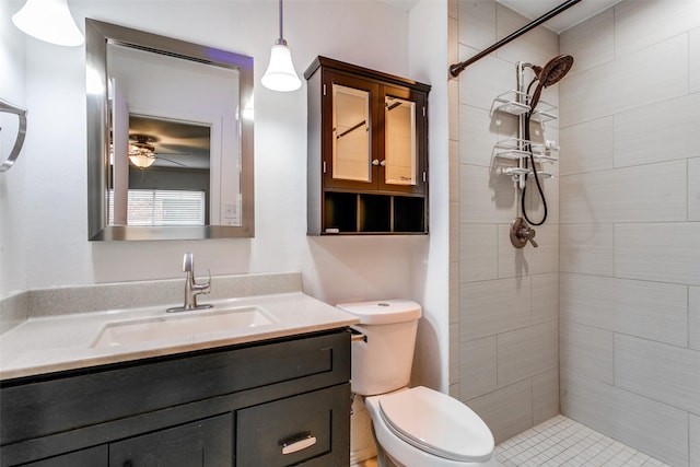 bathroom featuring toilet, vanity, ceiling fan, and tiled shower