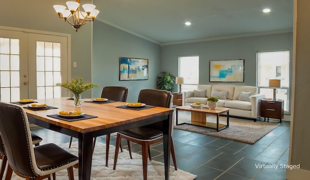 dining area featuring lofted ceiling, an inviting chandelier, dark tile patterned floors, ornamental molding, and french doors