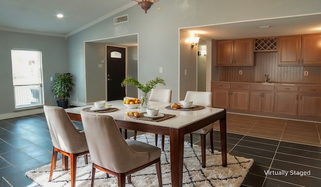 tiled dining room featuring sink, crown molding, and vaulted ceiling