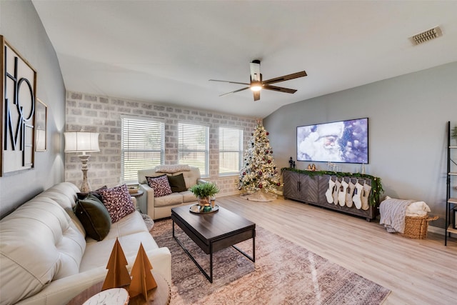 living room featuring brick wall, ceiling fan, vaulted ceiling, and light hardwood / wood-style flooring