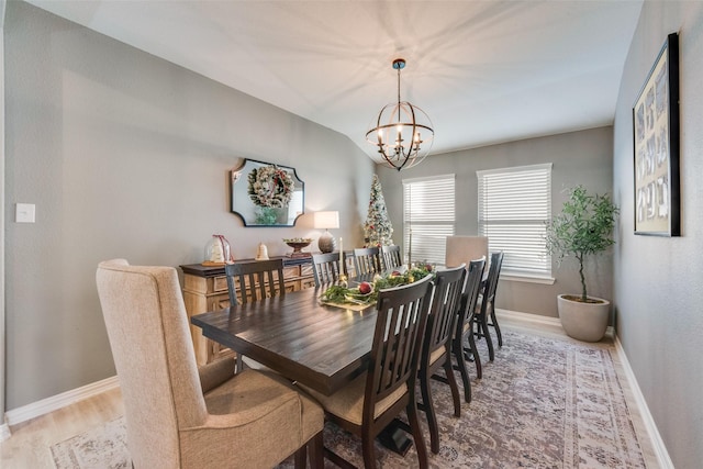 dining space featuring vaulted ceiling, an inviting chandelier, and hardwood / wood-style flooring