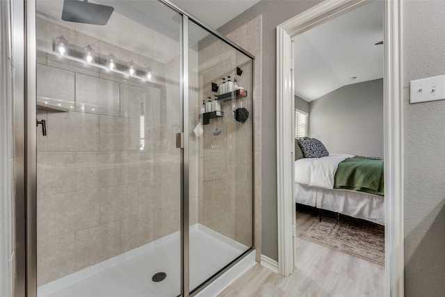 bathroom featuring walk in shower, vaulted ceiling, and wood-type flooring