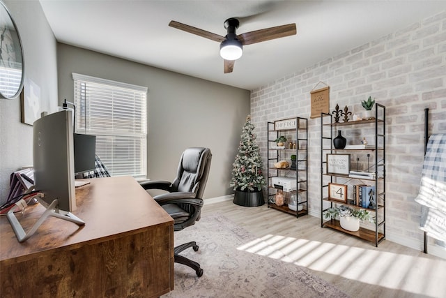 office area featuring brick wall, ceiling fan, and light wood-type flooring