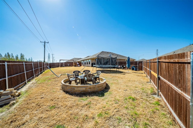 view of yard featuring a fire pit and a trampoline