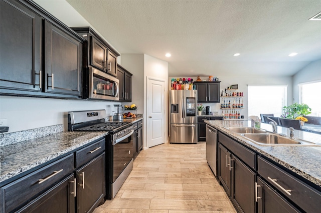 kitchen with sink, stainless steel appliances, a textured ceiling, and dark brown cabinetry