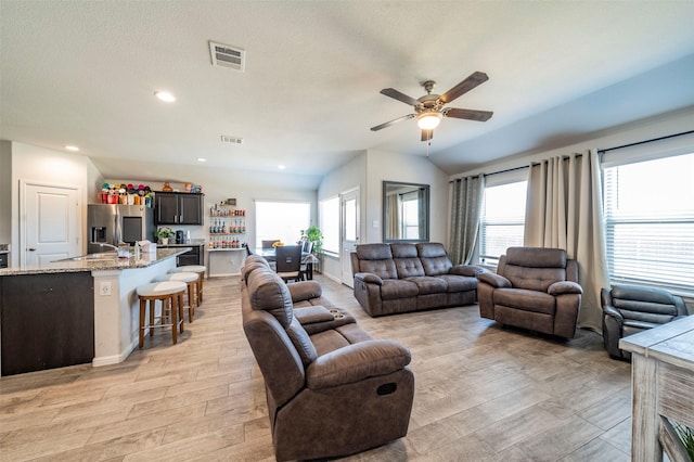 living room featuring ceiling fan, vaulted ceiling, and a textured ceiling