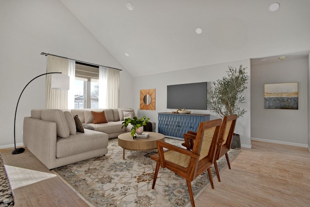 living room featuring high vaulted ceiling and light hardwood / wood-style floors