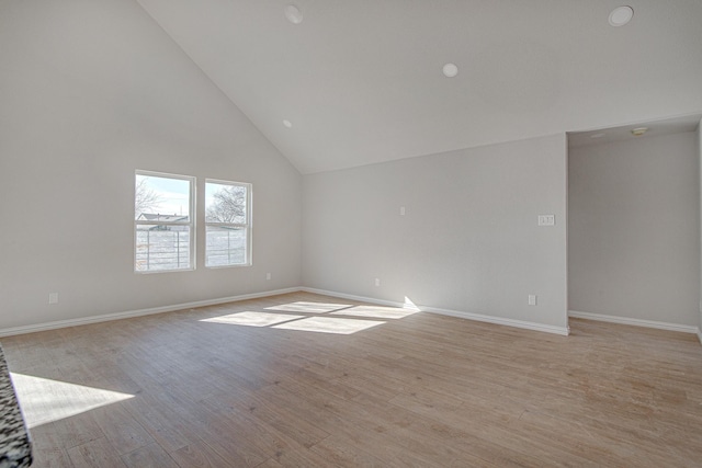 empty room with light hardwood / wood-style floors and high vaulted ceiling