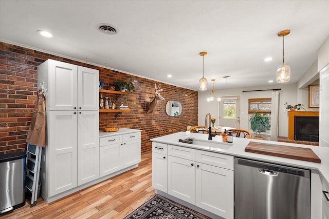 kitchen with sink, dishwasher, brick wall, and pendant lighting