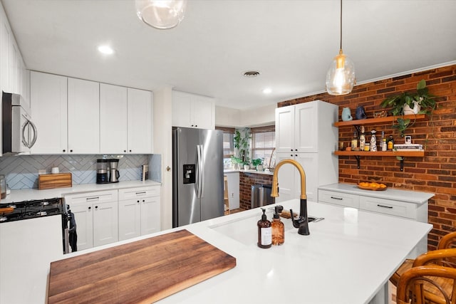 kitchen with hanging light fixtures, white cabinets, stainless steel appliances, and tasteful backsplash