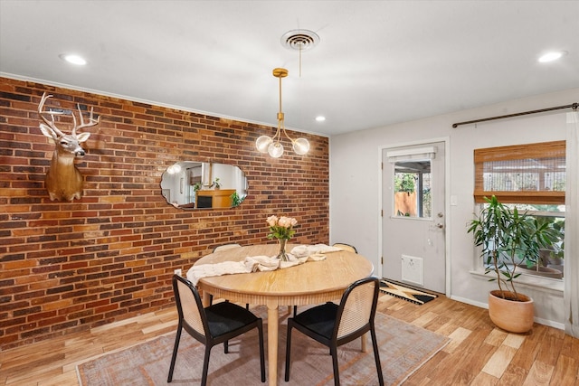 dining room with brick wall and light hardwood / wood-style flooring