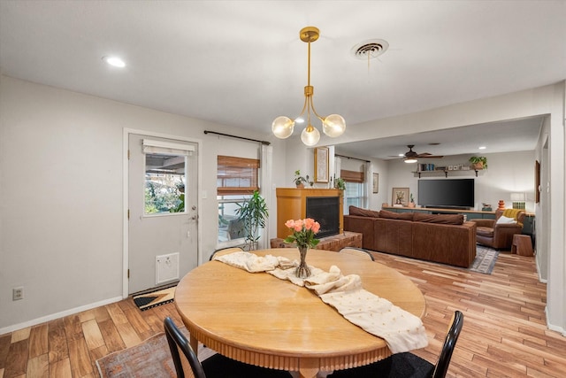 dining room featuring light wood-type flooring and ceiling fan with notable chandelier