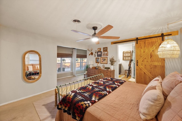 bedroom featuring ceiling fan, a barn door, and light colored carpet