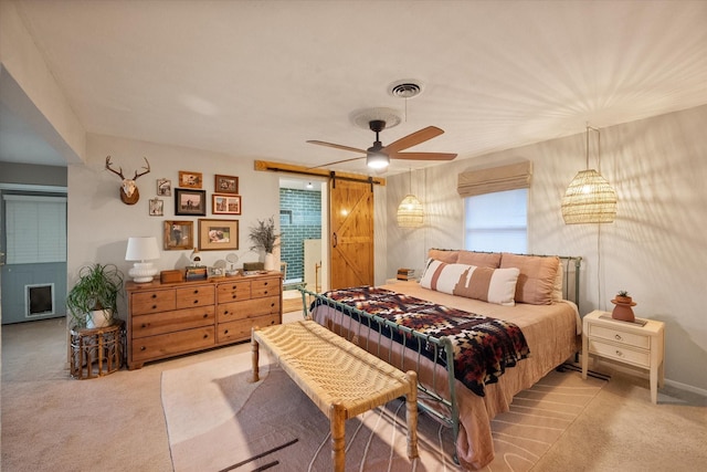 bedroom with ceiling fan, a barn door, and light carpet