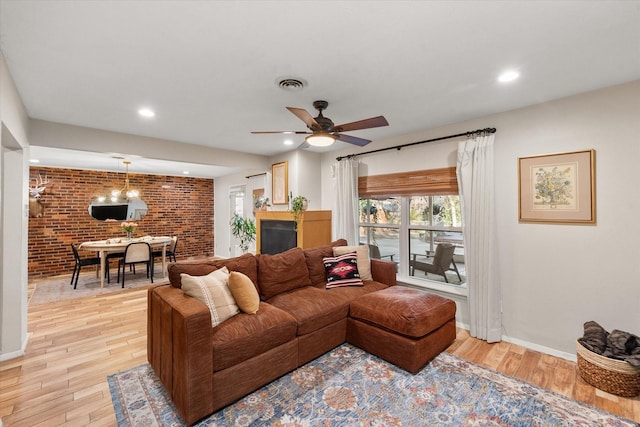 living room featuring light hardwood / wood-style floors, brick wall, and ceiling fan