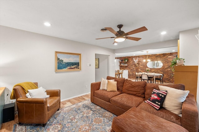 living room featuring hardwood / wood-style flooring, brick wall, and ceiling fan