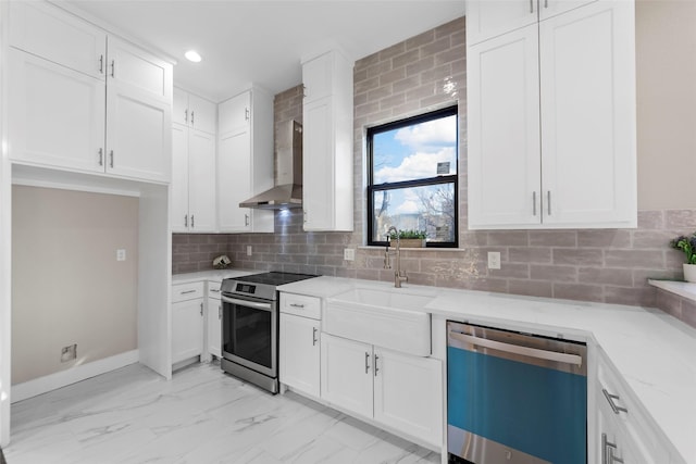 kitchen with appliances with stainless steel finishes, white cabinets, wall chimney exhaust hood, and sink