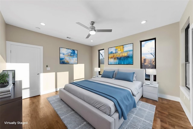 bedroom featuring dark hardwood / wood-style flooring, ceiling fan, and multiple windows