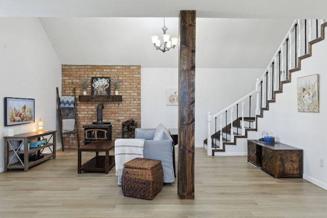 living room featuring light hardwood / wood-style floors, an inviting chandelier, and a wood stove