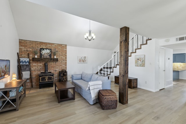 living room featuring light hardwood / wood-style floors, an inviting chandelier, and a wood stove