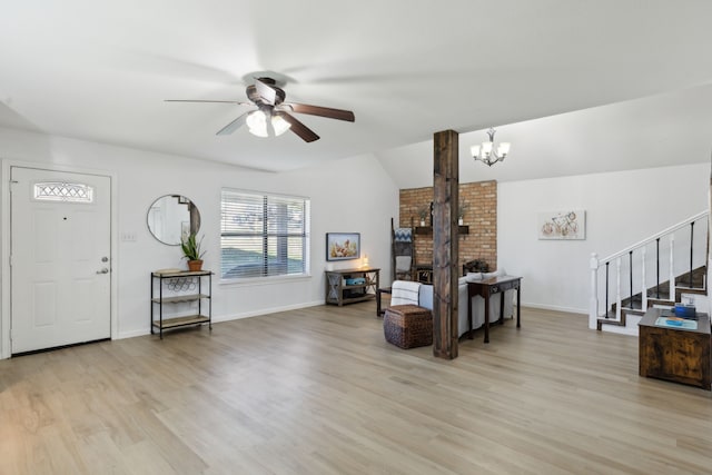 foyer entrance with ceiling fan with notable chandelier, vaulted ceiling, and light hardwood / wood-style floors