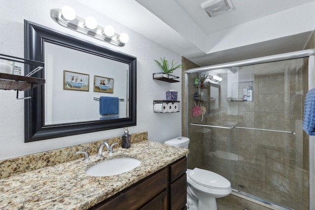 bathroom featuring toilet, vanity, and a shower with shower door