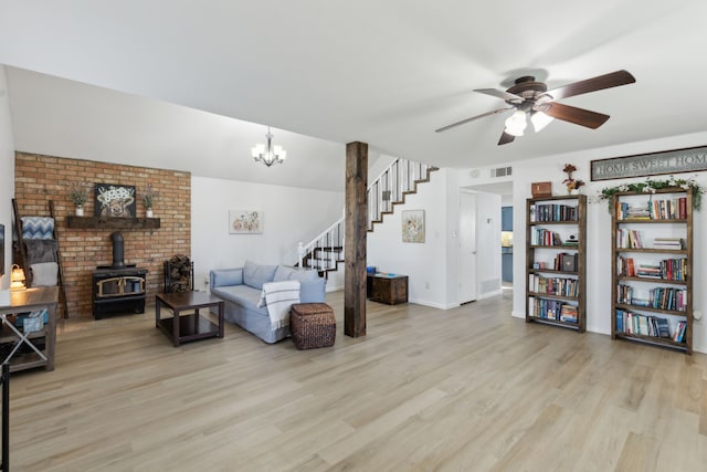 living room featuring ceiling fan with notable chandelier, light hardwood / wood-style floors, and a wood stove